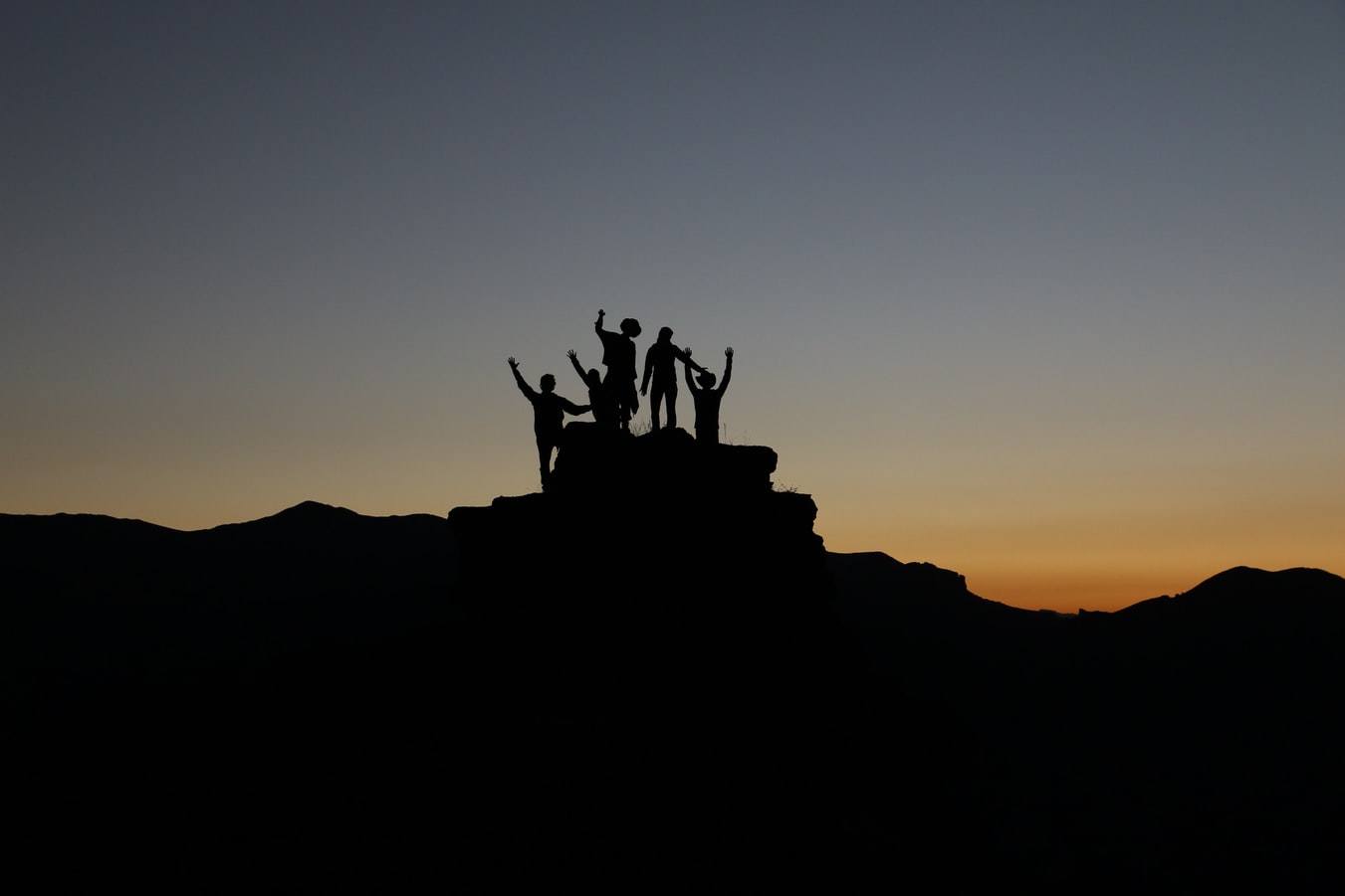 Group of adults standing on top of a rock together