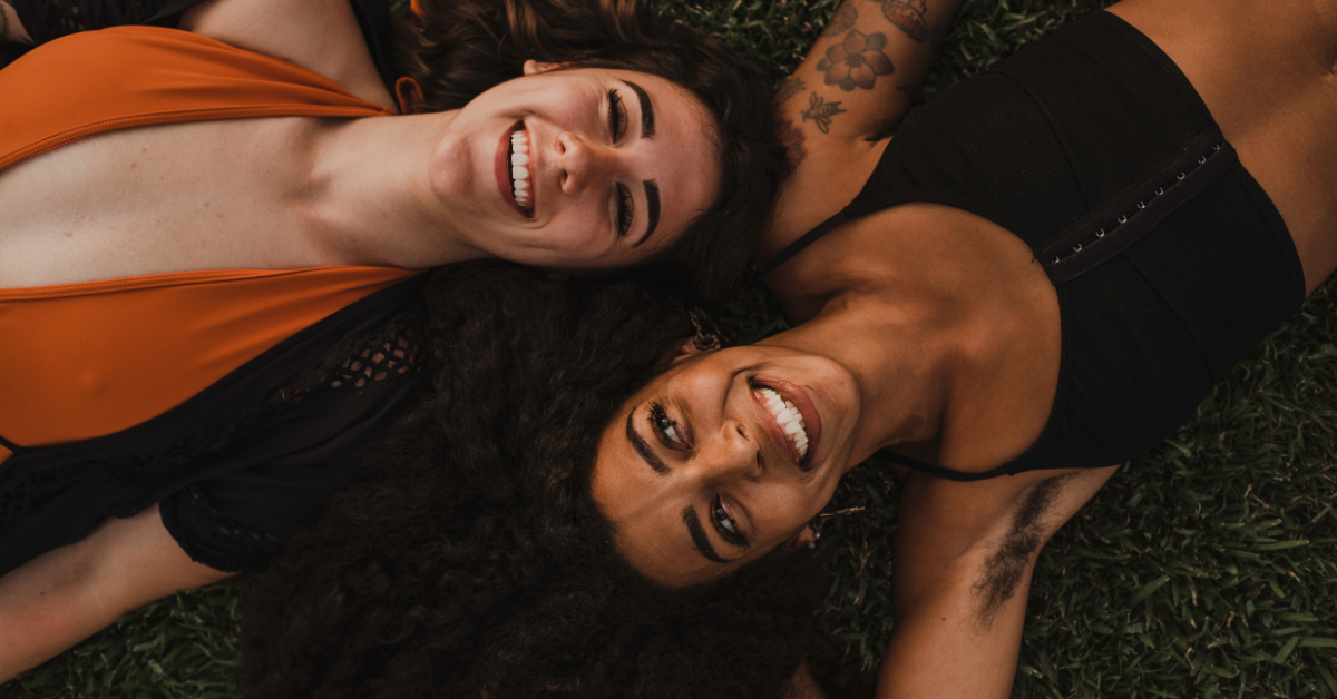 Two women laying down smiling up at the camera.