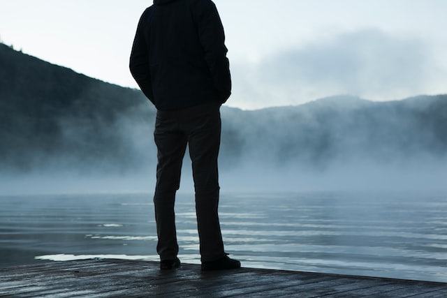 person standing on rock amid fog